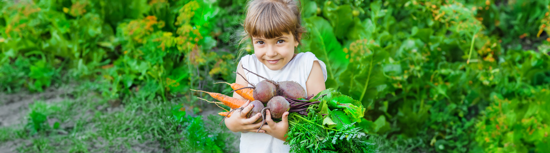 girl in garden with beets and carrots